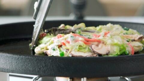 Frying Okonomiyaki on a cast iron griddle.