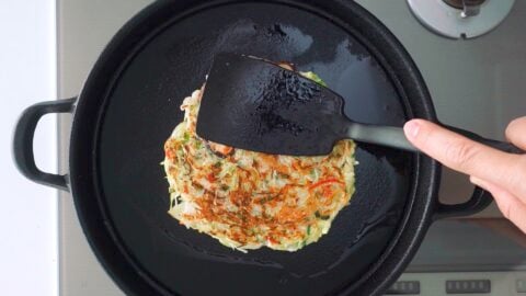 Pressing on Okonomiyaki with a spatula.