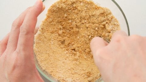 Mixing vegan parmesan cheese in a glass bowl.