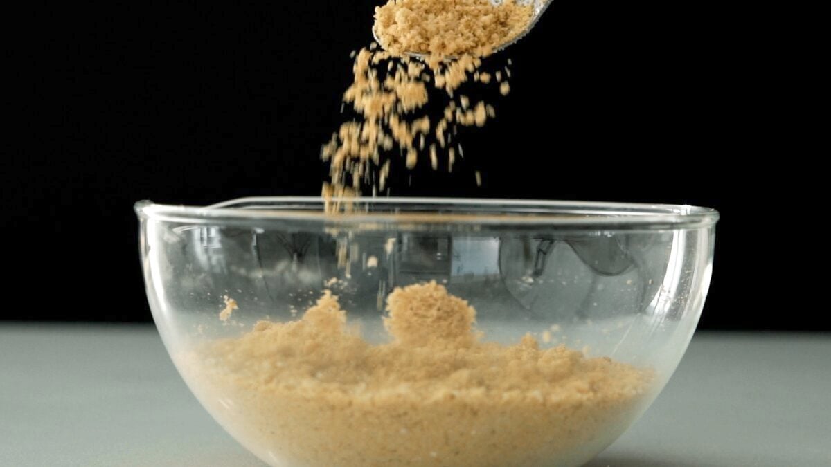 Sprinkling vegan parmesan cheese into a bowl.