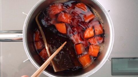 Removing konbu from broth with chopsticks.