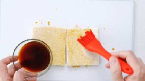 Brushing each tofu cutlet with seasoning.